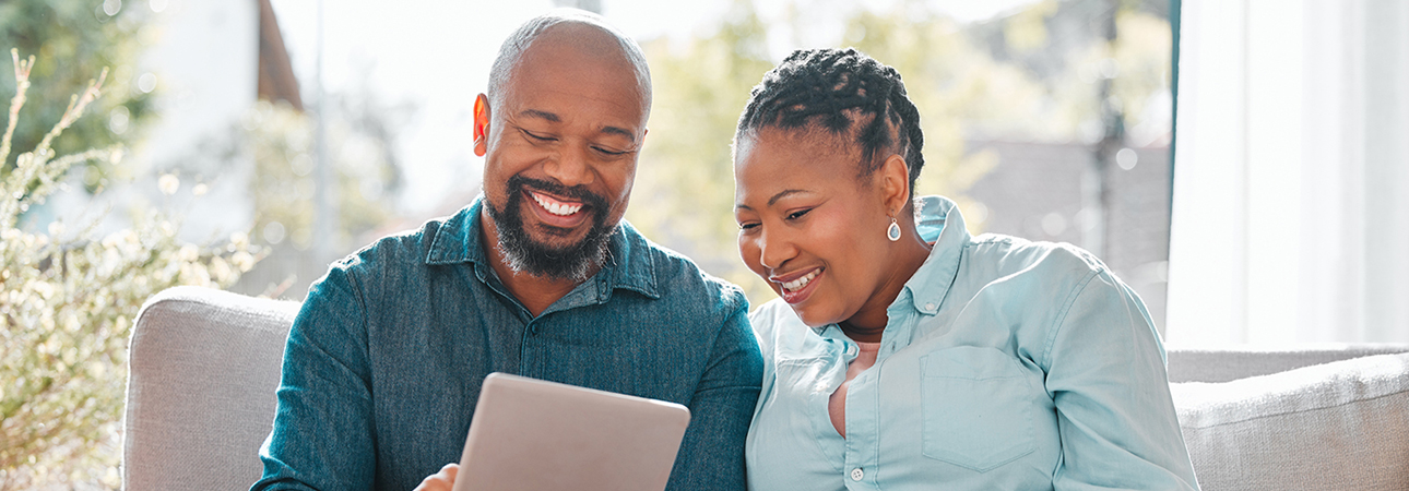 two smiling people looking at tablet